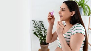 Young pregnant woman with dental floss in white bathroom