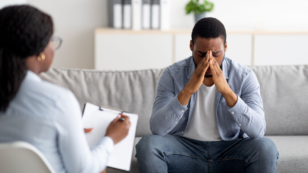 Desperate black man suffering from nevrous breakdown or depression, having session at psychologist's office, panorama Depression, posttraumatische Belastungsstörung