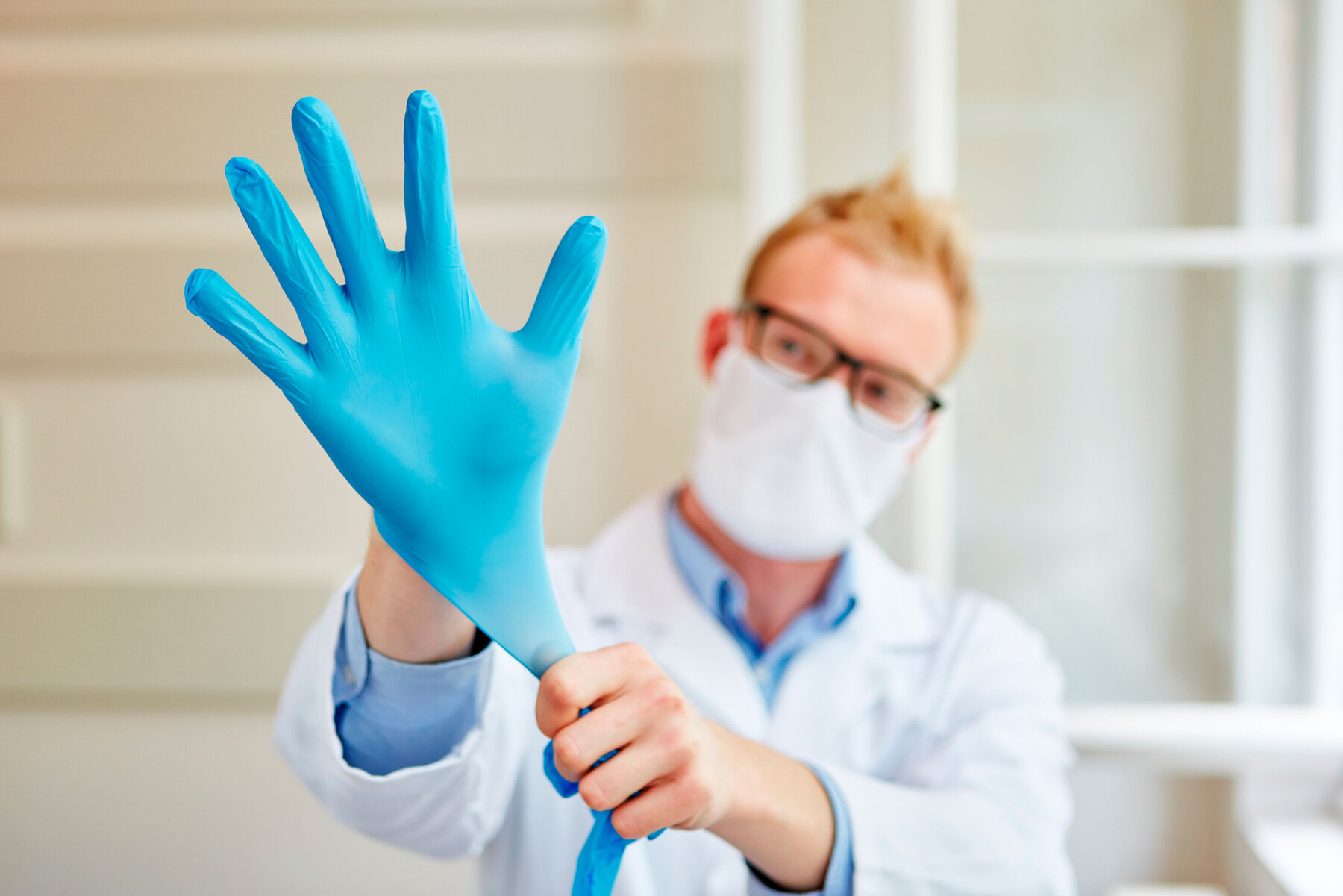 Arzt zieht sich Handschuhe als Arbeitsschutz für die Hygiene an