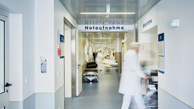 Notaufnahme Eingang Krankenhaus mit Arzt Rollstuhl und Patient in Bewegungsunschärfe auf dem Flur