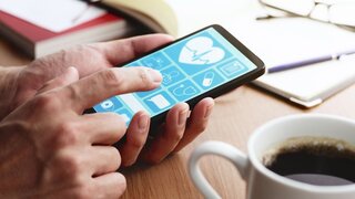 Gesundheits-App auf dem Smartphone-Bildschirm. Nahaufnahme von männlichen Händen, die den Smartphone-Bildschirm am Tisch berühren.