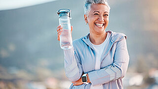 Fitness, happy or old woman with water bottle in nature to start training, exercise or hiking workout in New Zealand. Portrait, liquid or healthy senior person smiles with pride, goals or motivation.