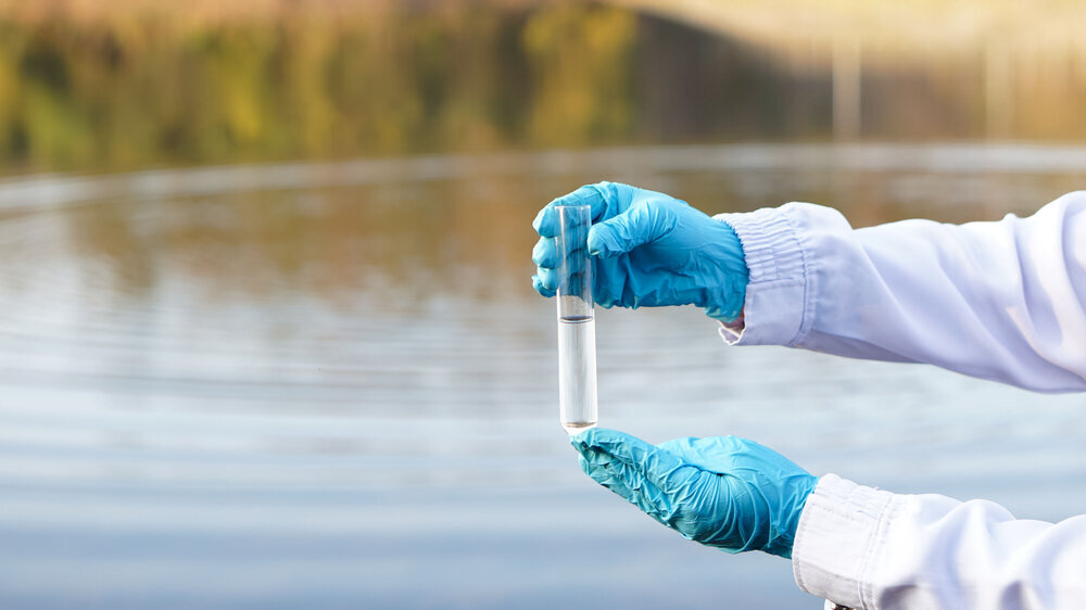 Die Hände des Nahaufnahme mit blauen Handschuhen halten Reagenzglasröhrchen, die Probenwasser am See enthalten. Es wird erwartet, dass Fälle von antimikrobieller Resistenz bis 2050 jährlich 10 Millionen zusätzliche direkte Todesfälle verursachen. Dies entspricht der Zahl der Todesfälle, die im Jahr 2020 weltweit durch Krebs verursacht wurden.