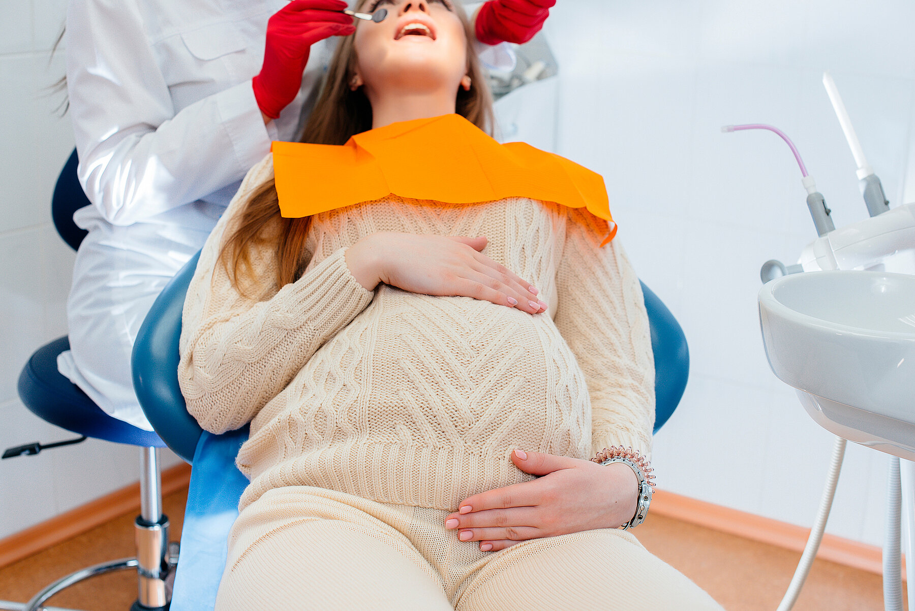 A professional dentist treats and examines the oral cavity of a pregnant girl in a modern dental office. Dentistry