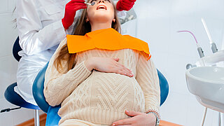 A professional dentist treats and examines the oral cavity of a pregnant girl in a modern dental office. Dentistry