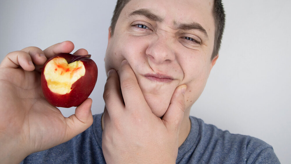 Mann beißt in Apfel und empfindet Zahnschmerzen. Mann beißt in Apfel und empfindet Zahnschmerzen.
