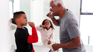 Großvater im Badezimmer, der im Pyjama seinen Enkelkindern die Zähne putzt