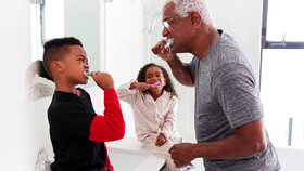 Großvater im Badezimmer, der im Pyjama seinen Enkelkindern die Zähne putzt