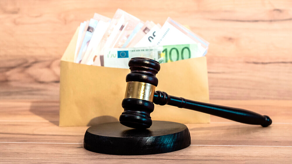 Ein Richterhammer vor einem Umschlag mit Euro-Banknoten. Ein Richterhammer vor einem Umschlag mit Euro-Banknoten.
