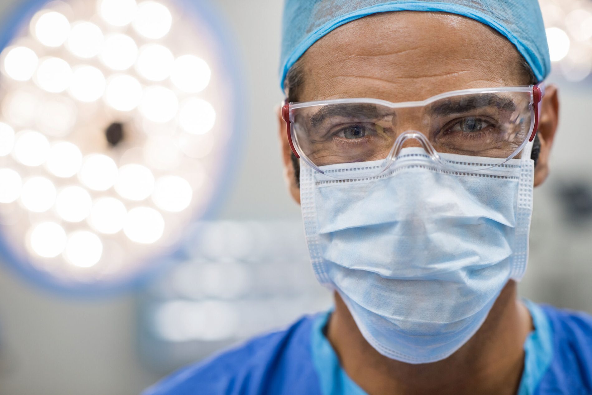 Close up face of surgeon man looking at camera with protective mask. Dental assistant with surgical mask and safety glasses in dental clinic. Happy successful surgeon in a operating room.