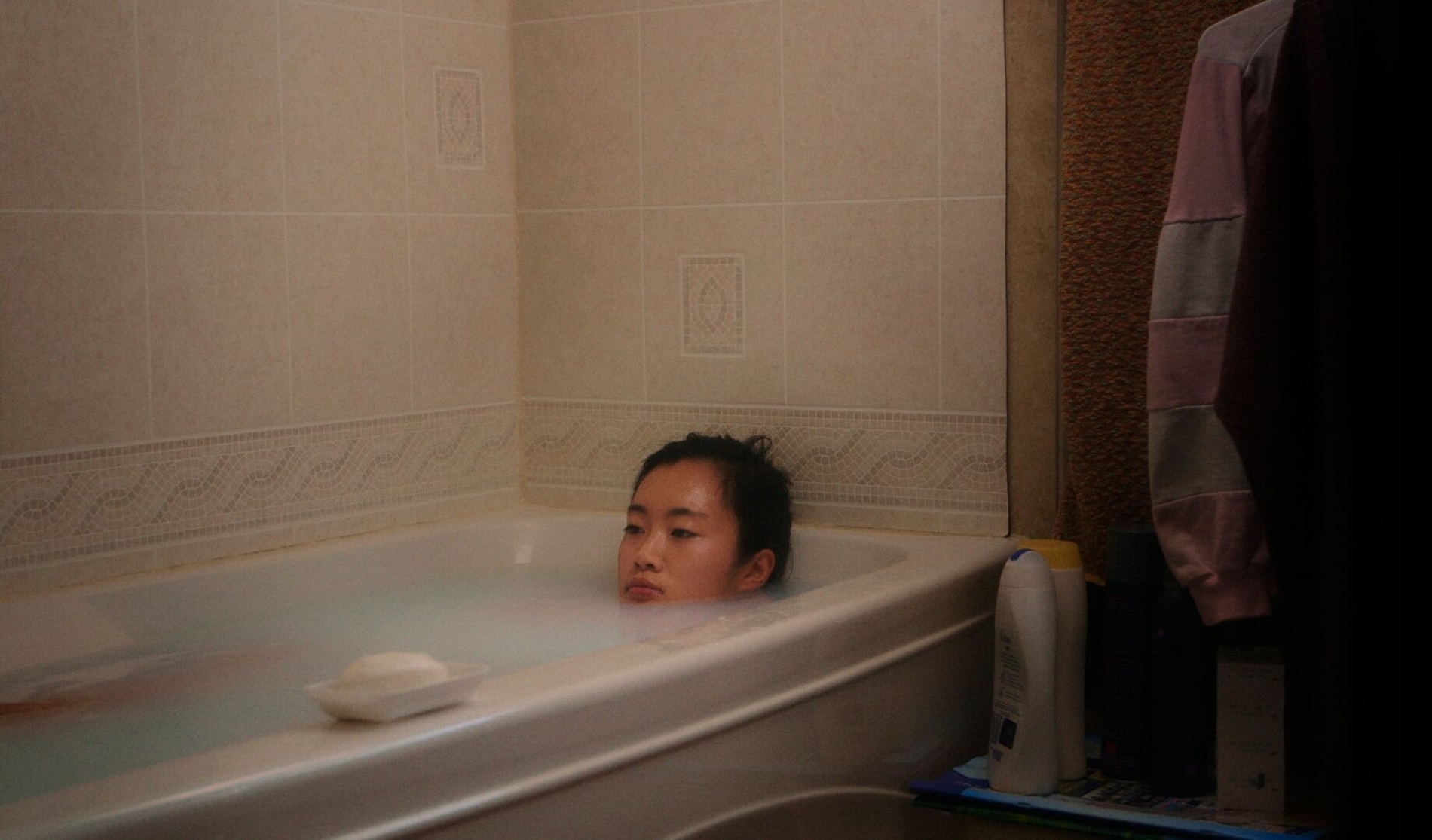 Wie kann man nach Jahren des Schweigens ins Gespräch kommen? Carol Nguyen interviewt ihre eigene Familie. Sie möchte verstehen, wie unausgesprochene Erfahrungen über Generationen wirken und wie Offenheit helfen kann, die Last zu teilen. Am Esstisch entsteht ein vorsichtiges Gespräch. Schmerz, Trauer und Erinnerungen werden erstmals ausgesprochen und gemeinsam betrachtet. Eine Familie findet langsam eine gemeinsame Sprache (Carol Nguyen, Crying at the Dinner Table, 2019, Videostill, Travelling Distribution).